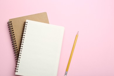 Notebooks and pencil on pink background, top view. Space for text