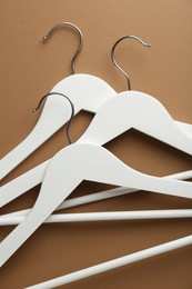 White hangers on brown background, top view