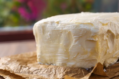 Photo of Piece of tasty homemade butter on parchment, closeup view