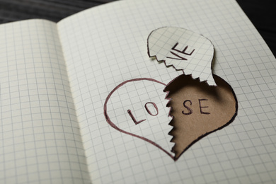 Photo of Broken heart with words LOVE and LOSE in notebook on table, closeup. Relationship problems concept