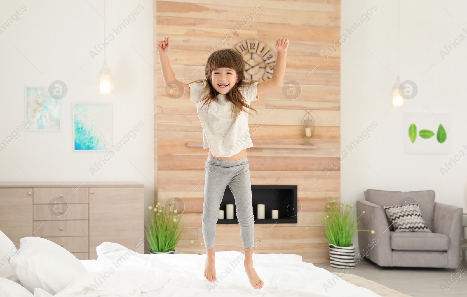 Photo of Cute little girl jumping on bed at home