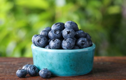 Photo of Tasty fresh blueberries on wooden table outdoors, closeup