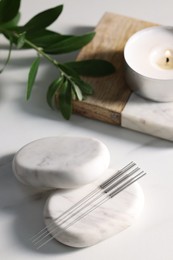 Stones with acupuncture needles on white table