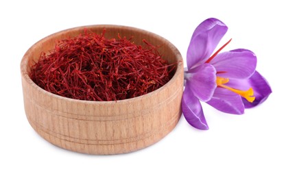 Dried saffron in wooden bowl and crocus flower on white background