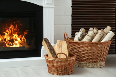 Photo of Firewood in wicker baskets near fireplace indoors