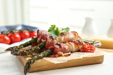 Photo of Oven baked asparagus wrapped with bacon on white wooden table