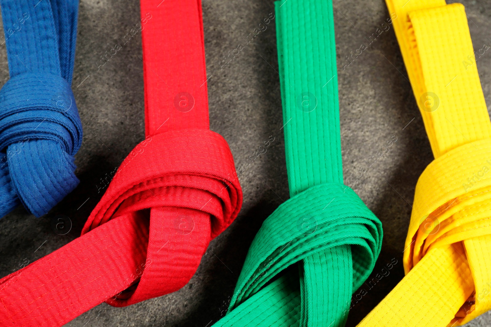 Photo of Colorful karate belts on gray background, flat lay