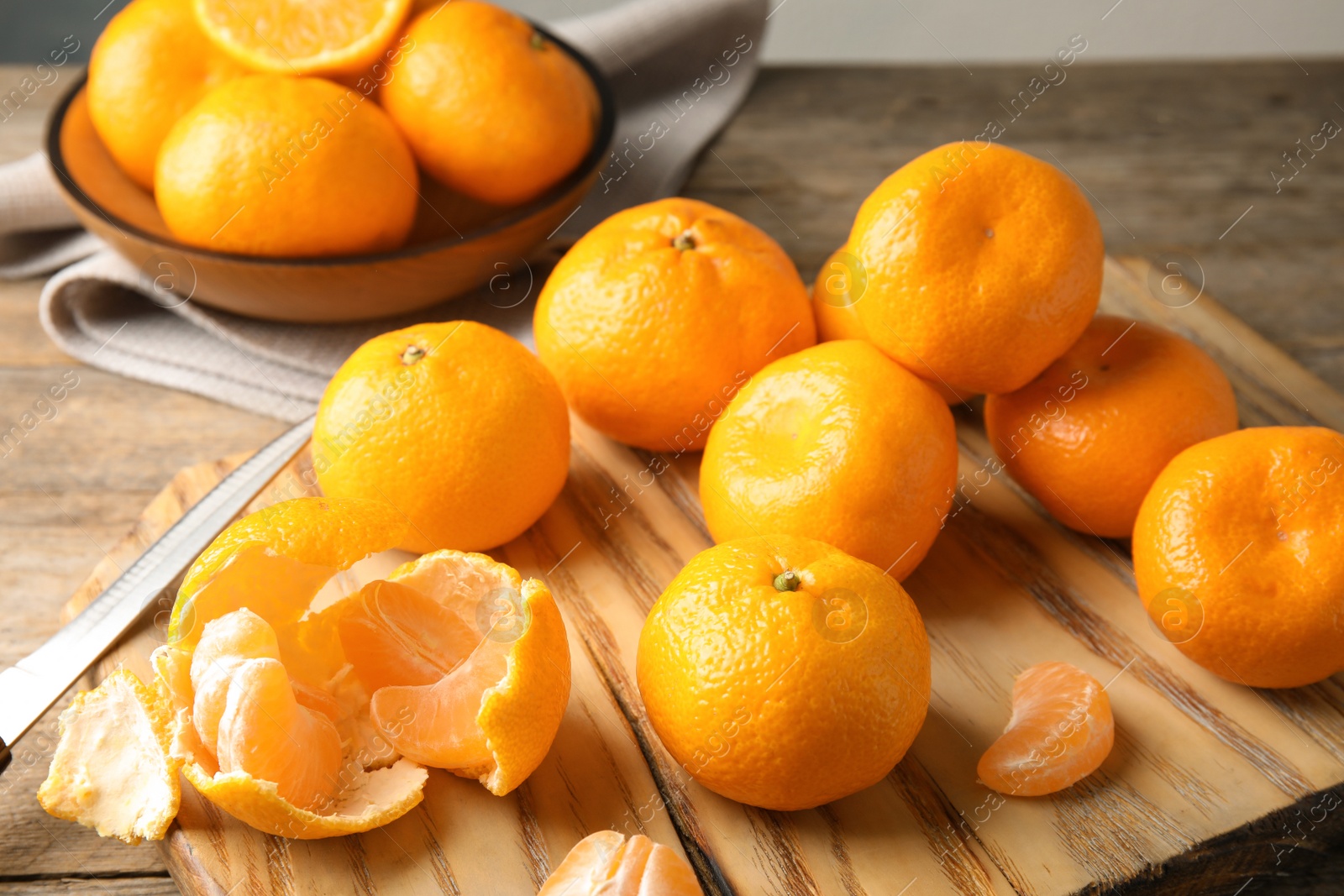 Photo of Wooden board with ripe tangerines on table