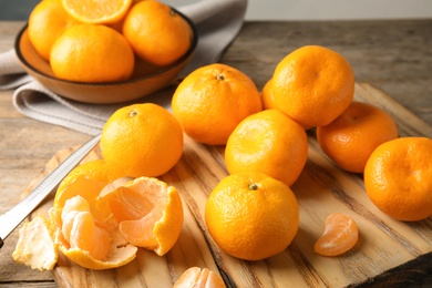 Wooden board with ripe tangerines on table