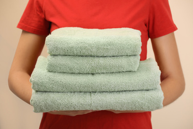 Woman holding fresh towels on color background, closeup