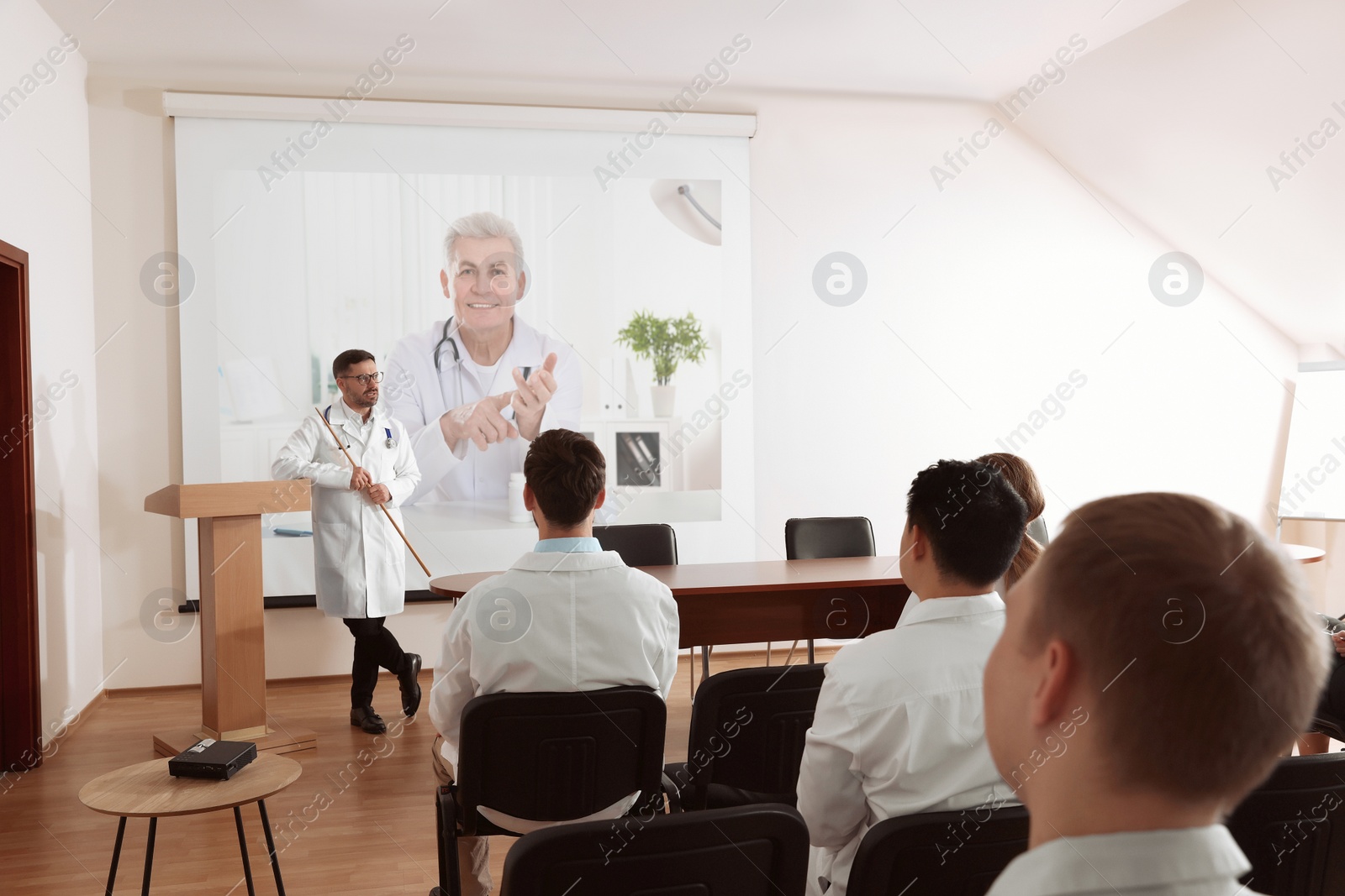 Image of Lecture with online participant. Doctors in meeting room. Using projector for videoconference