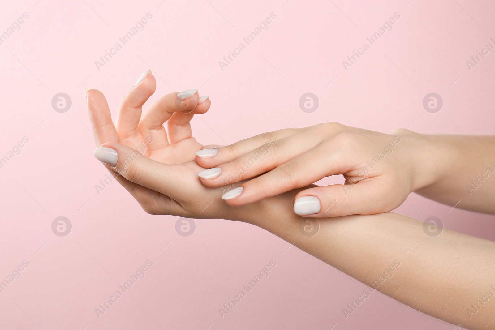 Photo of Woman with white polish on nails against pink background, closeup