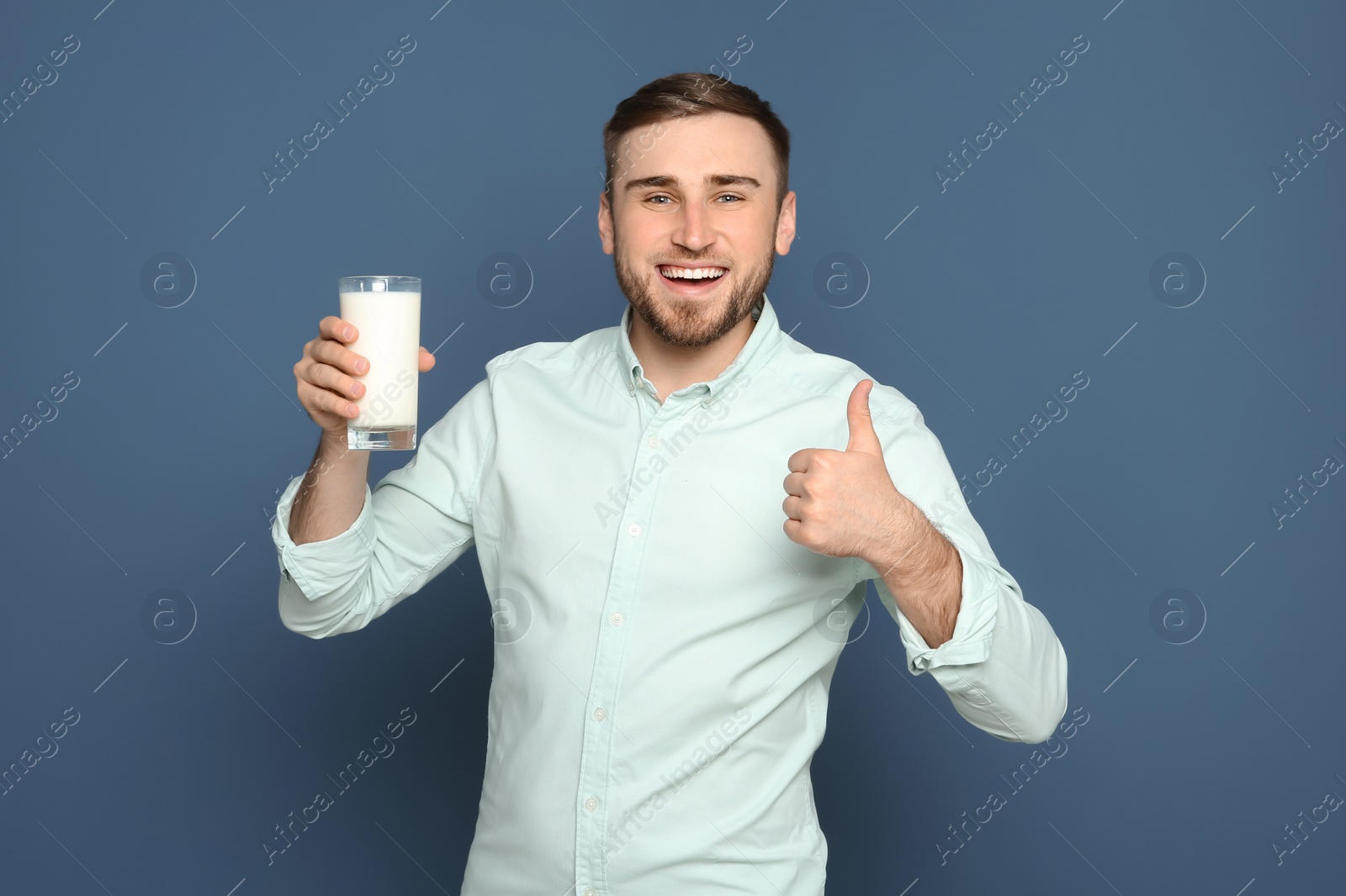 Photo of Young man with glass of tasty milk on color background