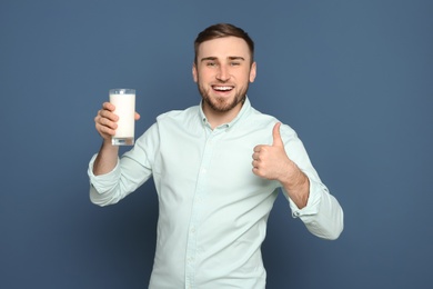 Photo of Young man with glass of tasty milk on color background