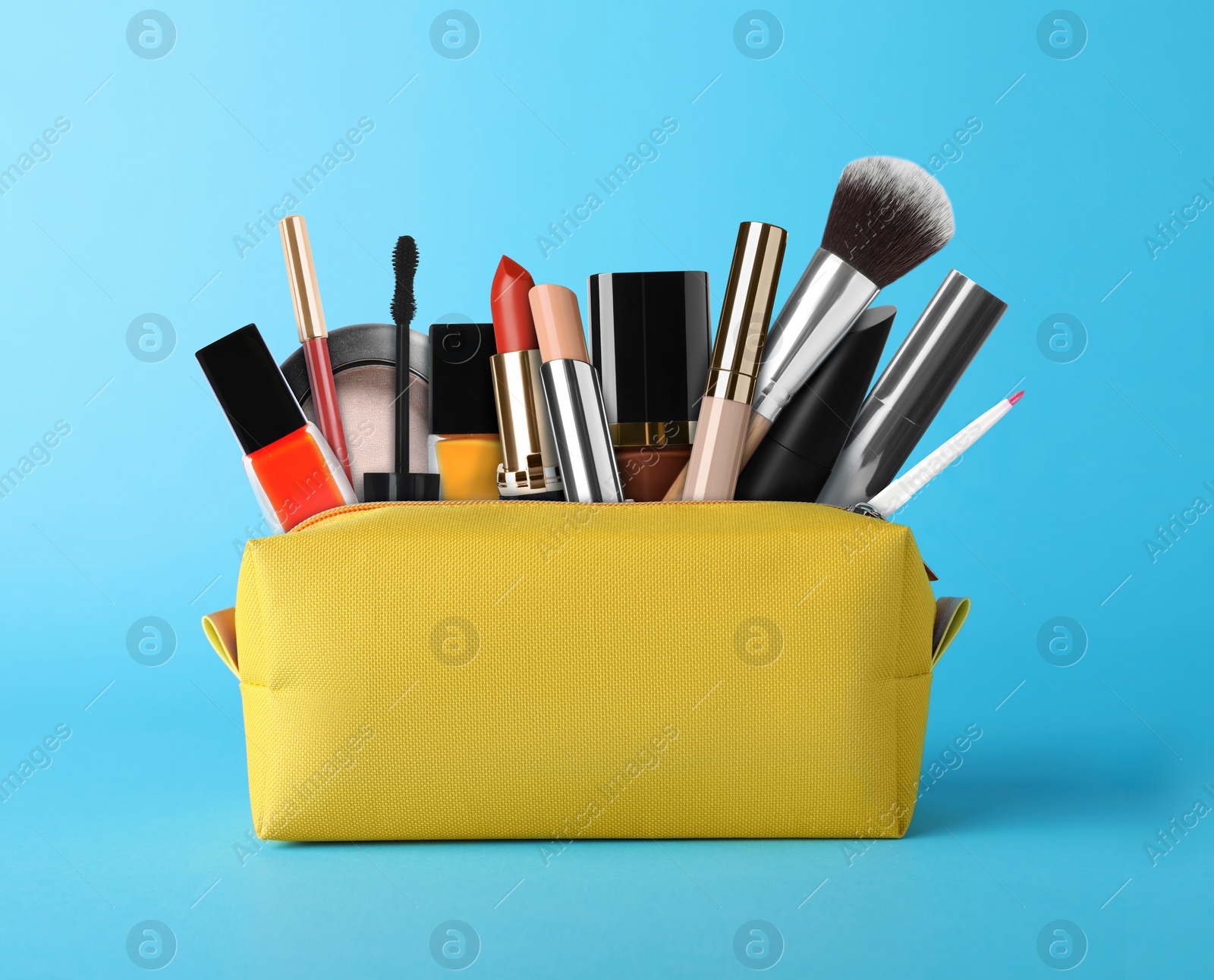 Image of Cosmetic bag filled with makeup products on light blue background