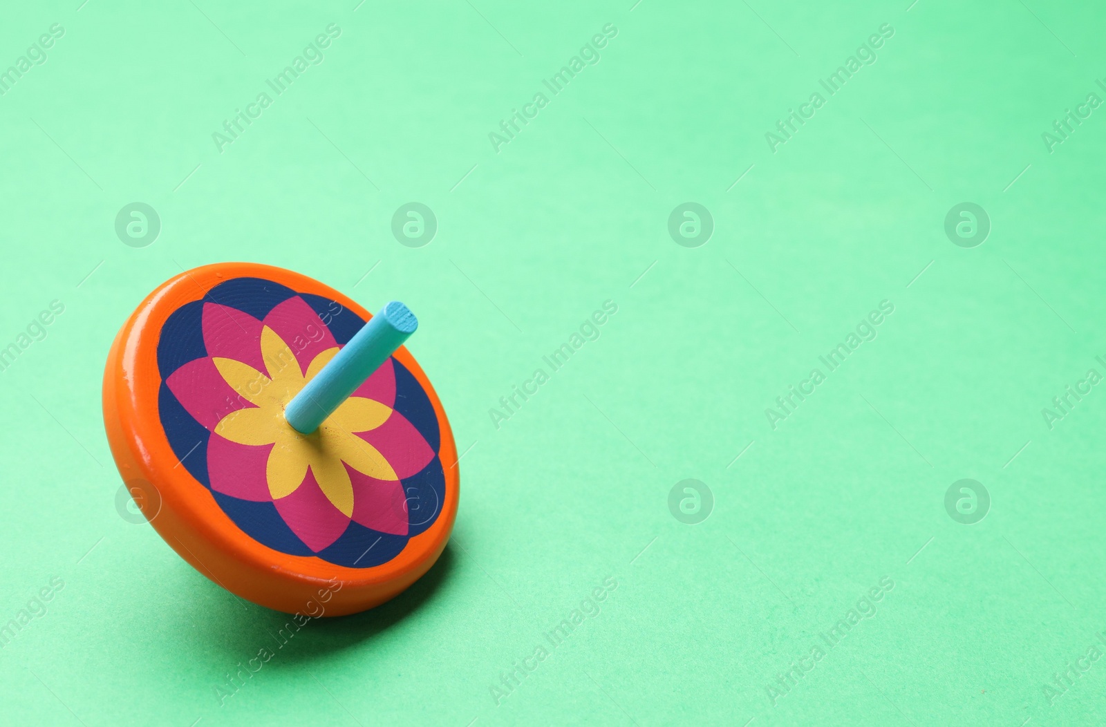 Photo of One colorful spinning top on green background, space for text