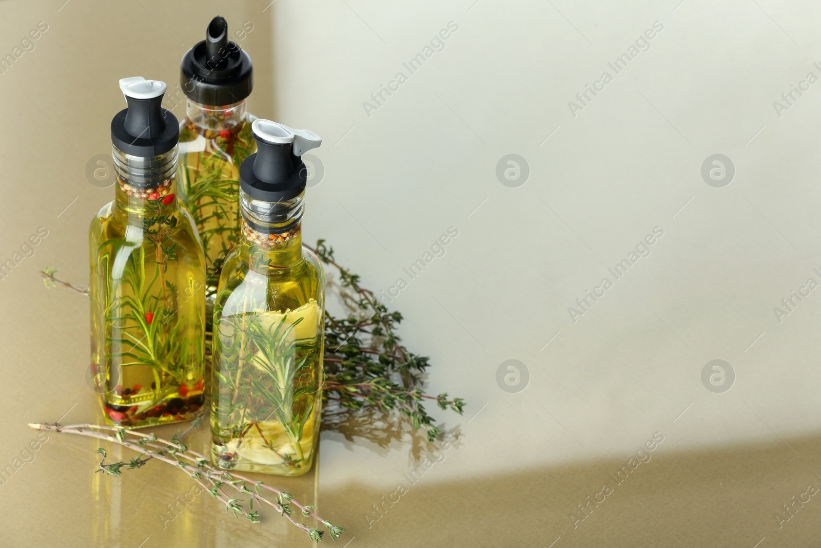 Photo of Cooking oil with different spices and herbs in bottles on colorful table. Space for text