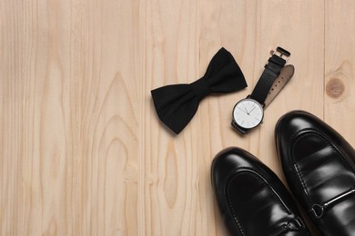 Photo of Stylish black bow tie, shoes and wristwatch on wooden background, flat lay. Space for text