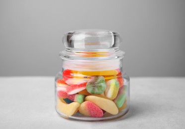 Photo of Tasty jelly candies in jar on light grey table, closeup