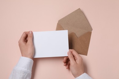 Woman with blank card at beige table, top view. Space for text