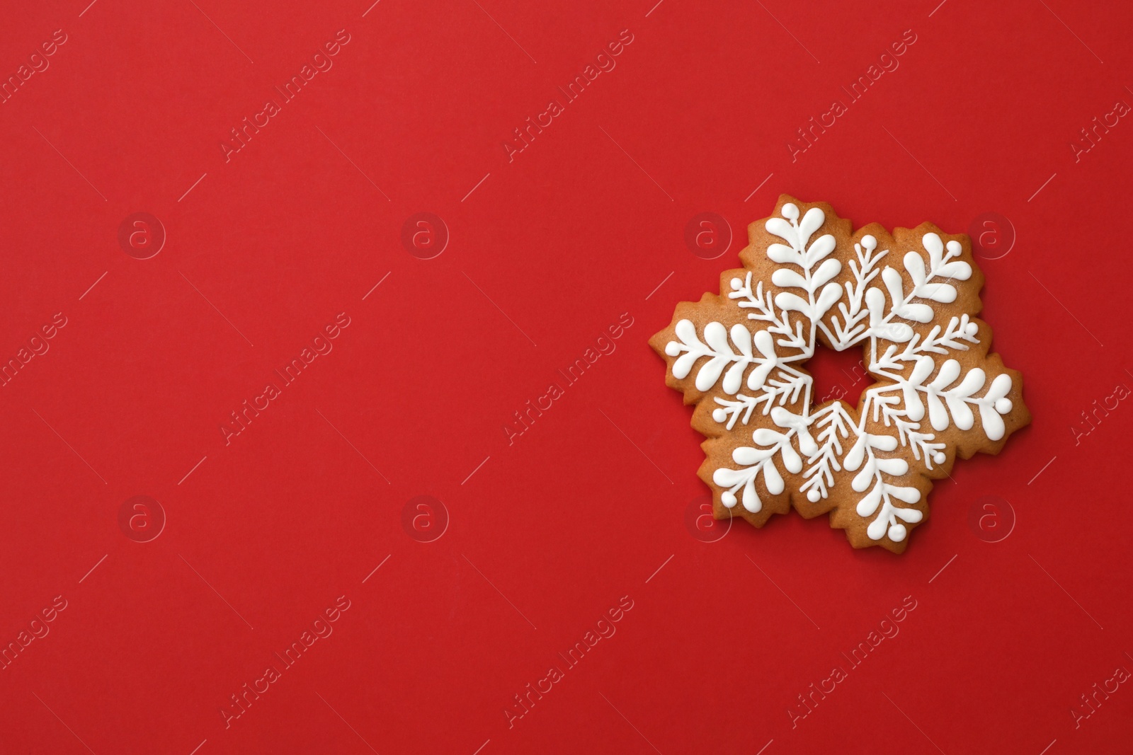 Photo of Christmas snowflake shaped gingerbread cookie on red background, top view. Space for text