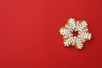 Photo of Christmas snowflake shaped gingerbread cookie on red background, top view. Space for text