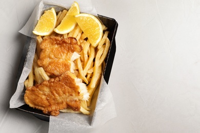 Photo of Container with British traditional fish and potato chips on light background, top view. Space for text