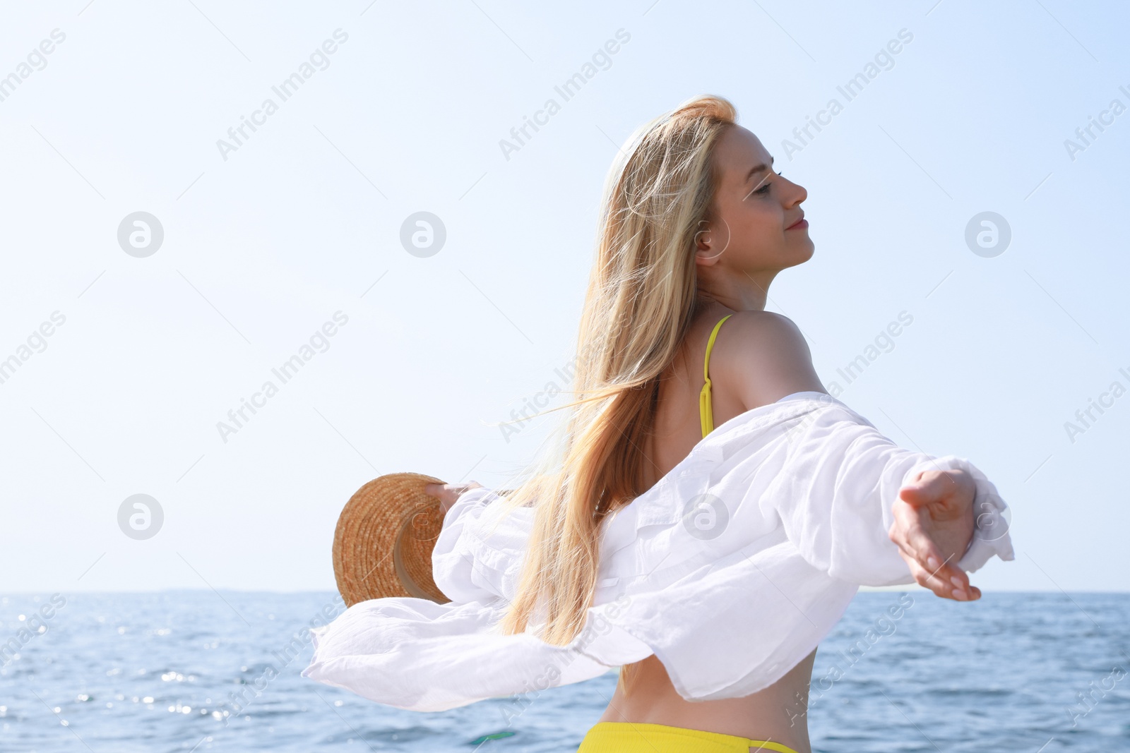 Photo of Beautiful young woman with straw hat near sea on sunny day in summer