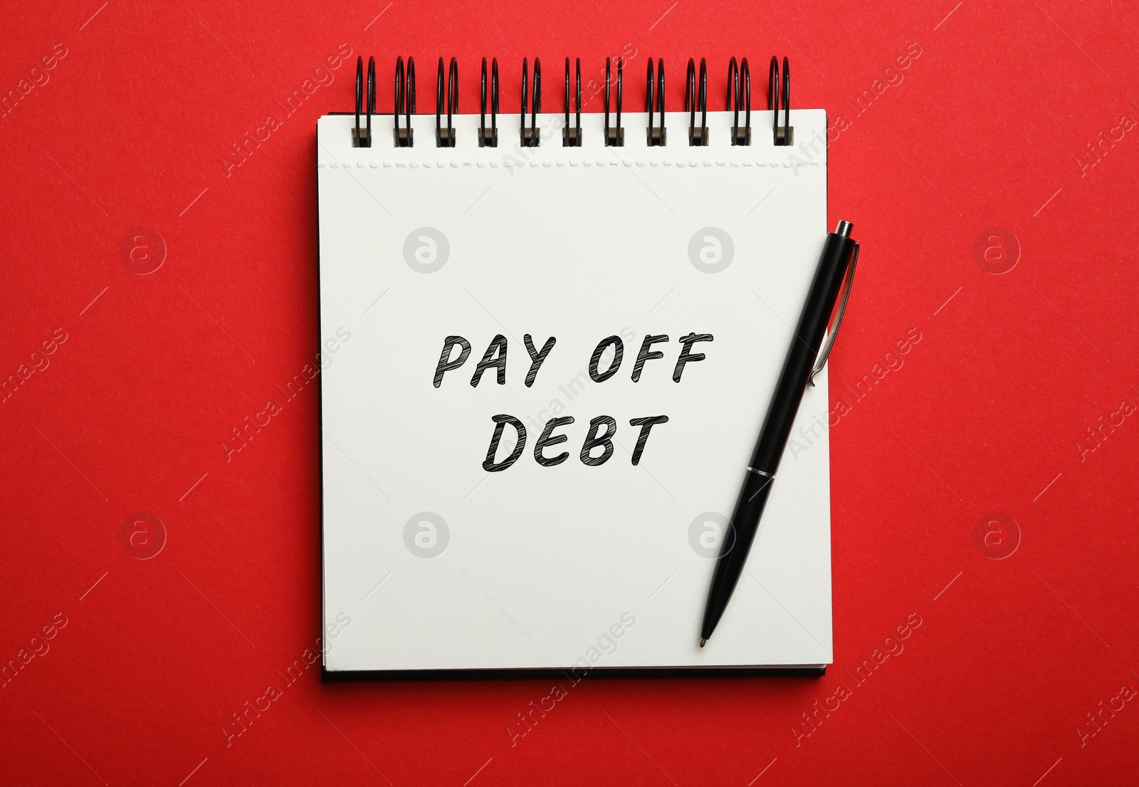 Image of Notebook with phrase Pay Off Debt and pen on red background, top view