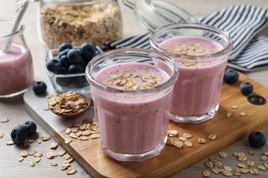 Photo of Glasses of tasty blueberry smoothie with oatmeal on table