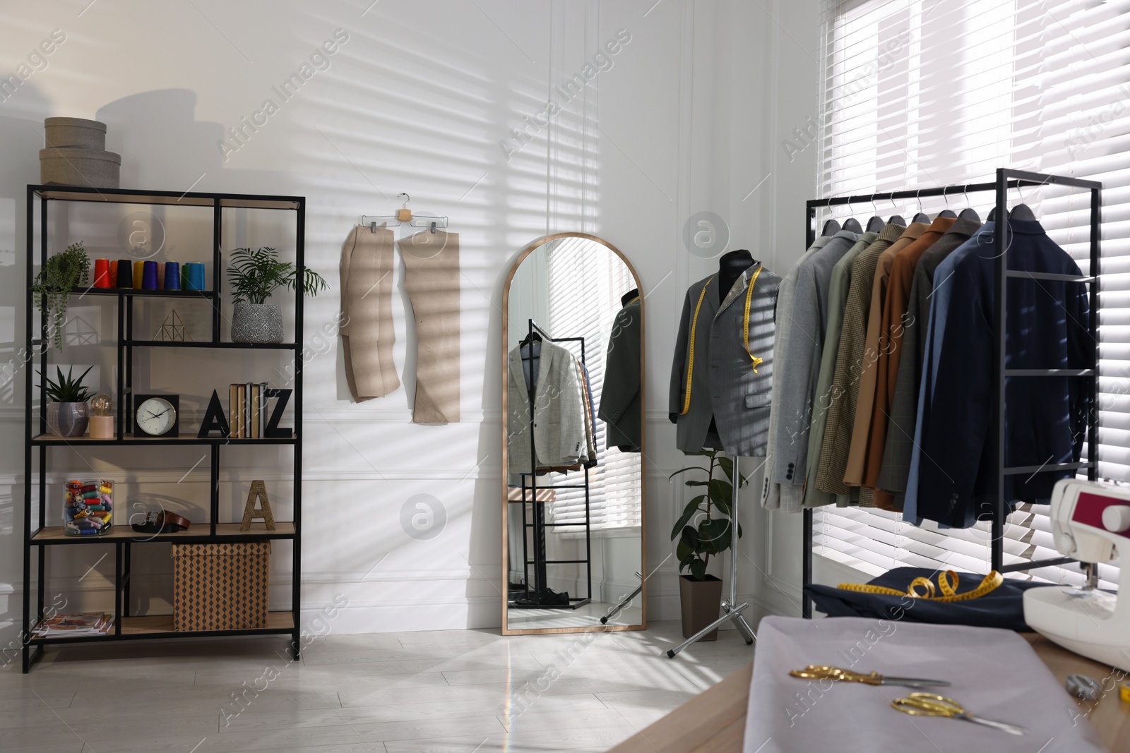 Photo of Tailor shop interior with mannequin and male suits on rack