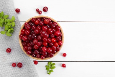 Photo of Fresh ripe cranberries and branches on white wooden table, top view. Space for text