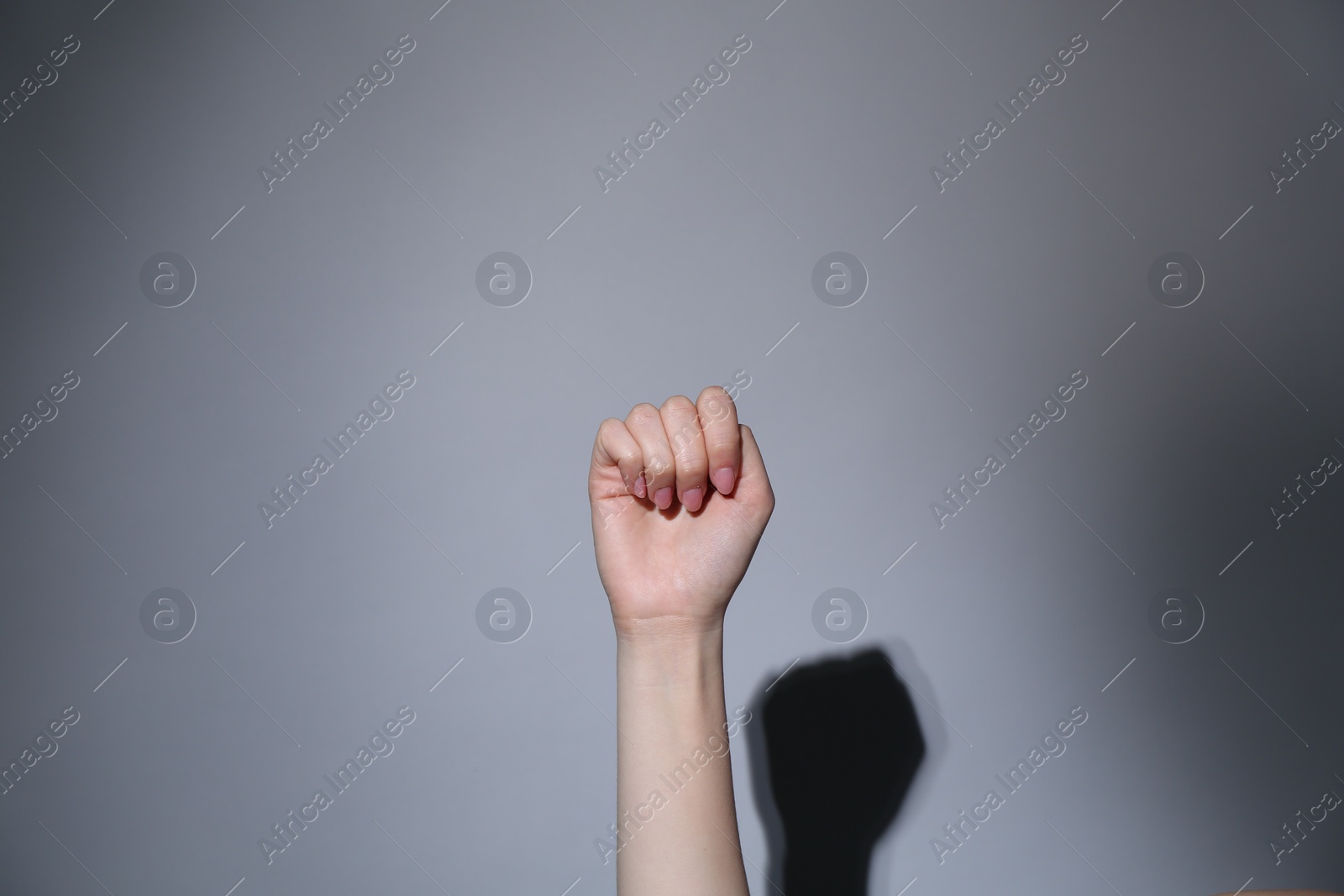 Photo of SOS gesture. Woman showing signal for help on grey background, closeup