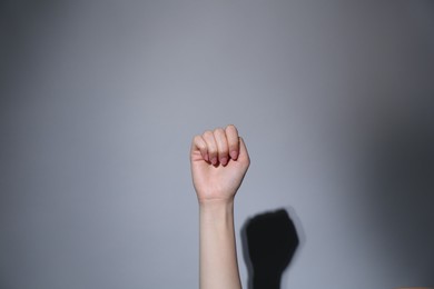 Photo of SOS gesture. Woman showing signal for help on grey background, closeup