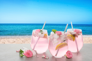 Image of Tasty refreshing drink on table against sandy beach