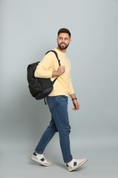 Photo of Young man with stylish backpack walking on light grey background