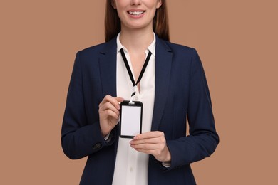 Woman with blank badge on light brown background, closeup