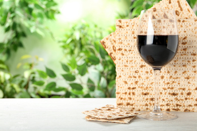 Traditional Matzos and glass of wine on white wooden table, space for text. Pesach (Passover) celebration