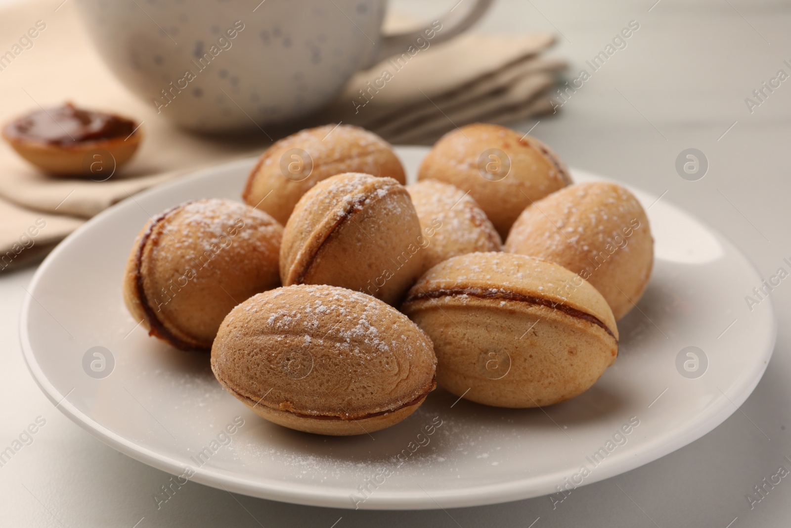 Homemade walnut shaped cookies with condensed milk on white table, closeup Photo of Homemade walnut shaped cookies with condensed milk on white table, closeup
