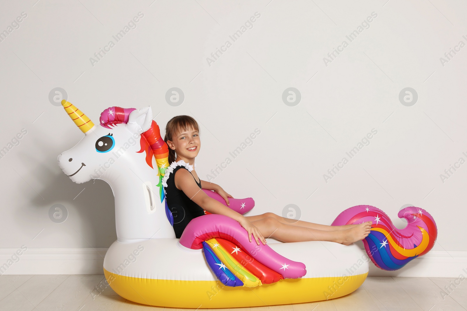 Photo of Cute little girl on bright inflatable ring near light wall