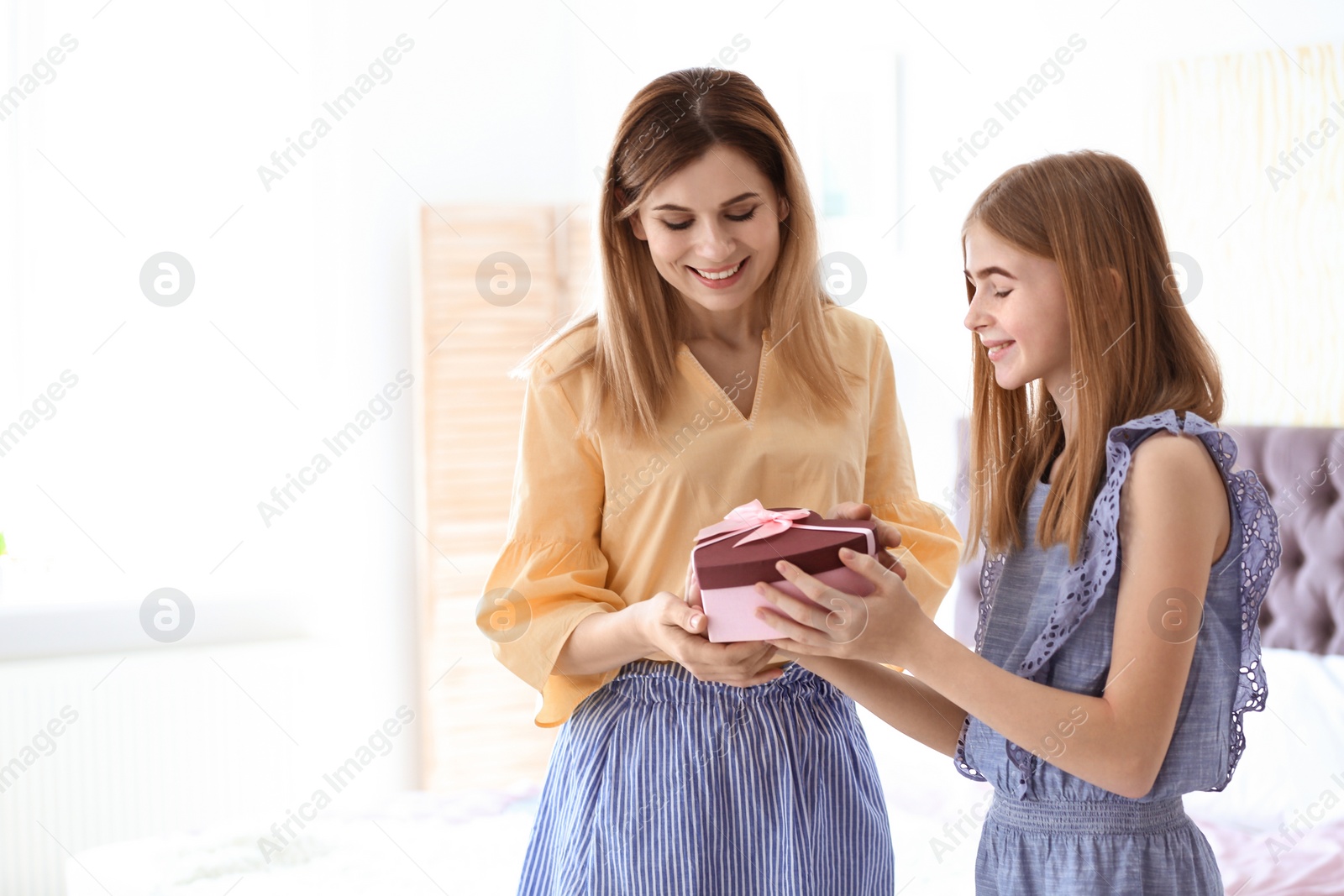 Photo of Teenage daughter congratulating happy woman on Mother's Day at home