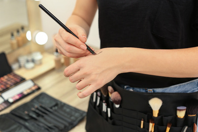 Photo of Makeup artist making swatch on hand with professional tool indoors, closeup