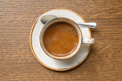 Photo of Cup of aromatic coffee on wooden table, top view