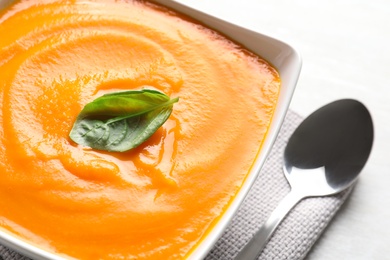 Bowl with tasty pumpkin soup on light background, closeup