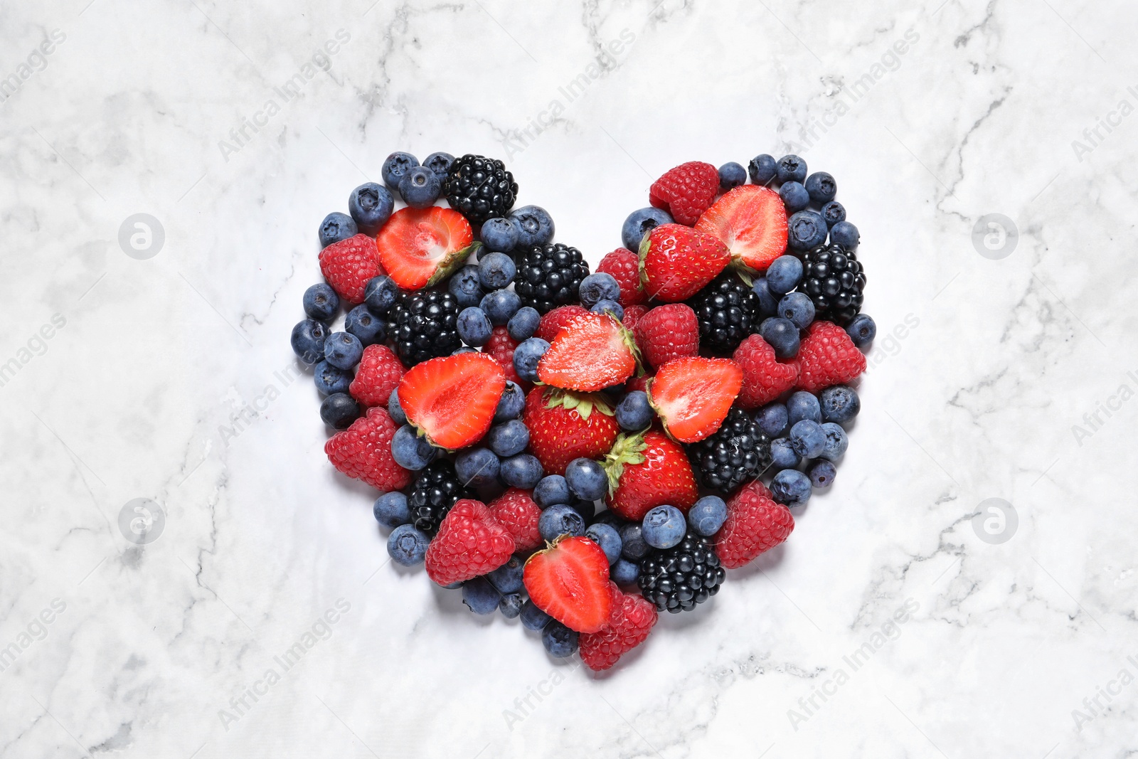 Photo of Heart made of different fresh ripe berries on white marble table, top view