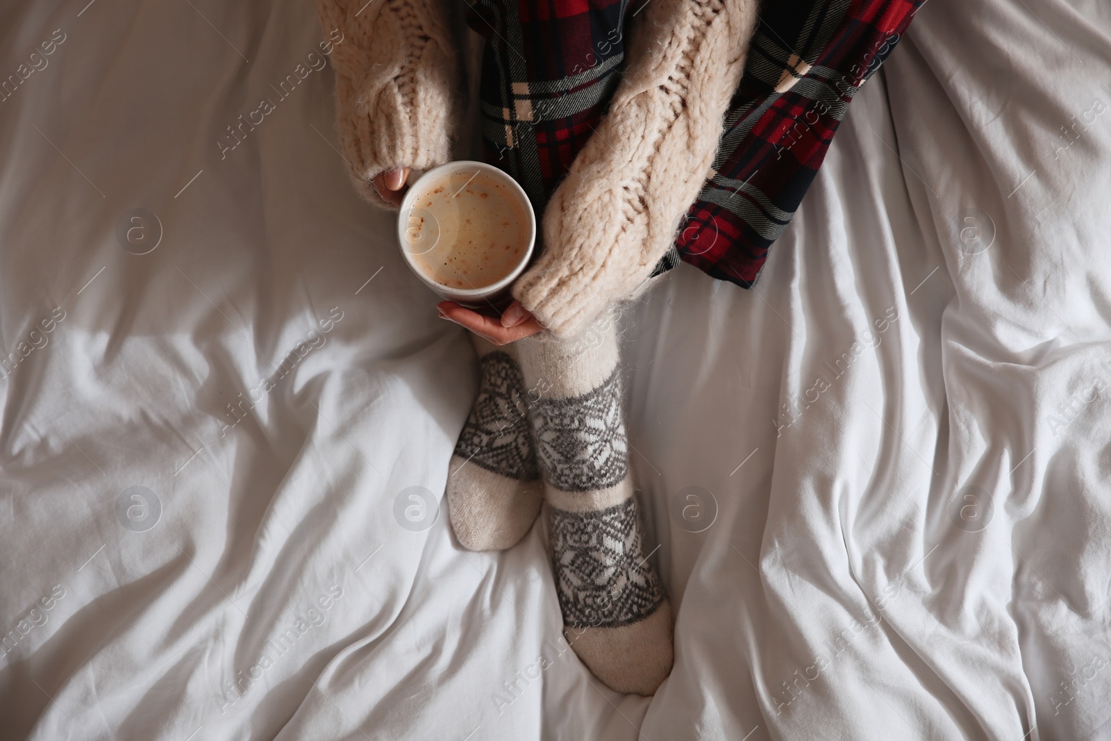 Photo of Woman with cup of coffee on soft blanket, top view