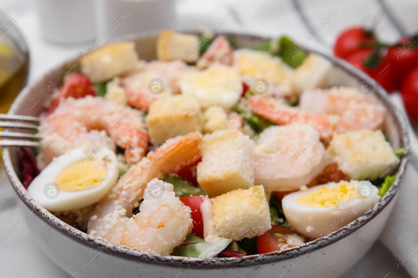 Photo of Delicious Caesar salad with shrimps served in bowl, closeup