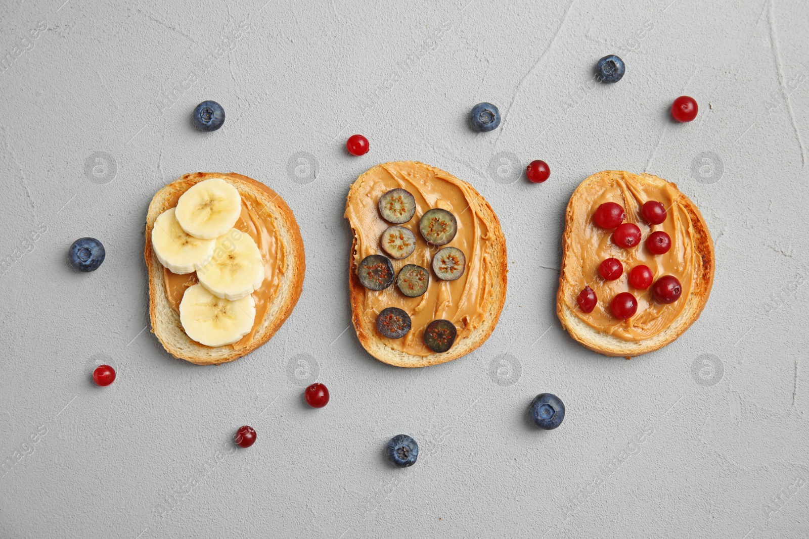 Photo of Slices of bread with different toppings on grey table, flat lay