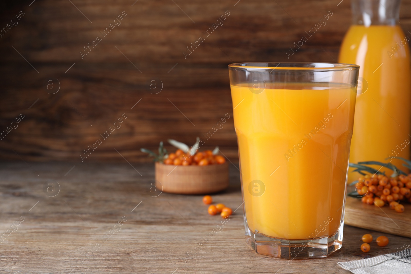 Photo of Delicious sea buckthorn juice on wooden table, closeup. Space for text
