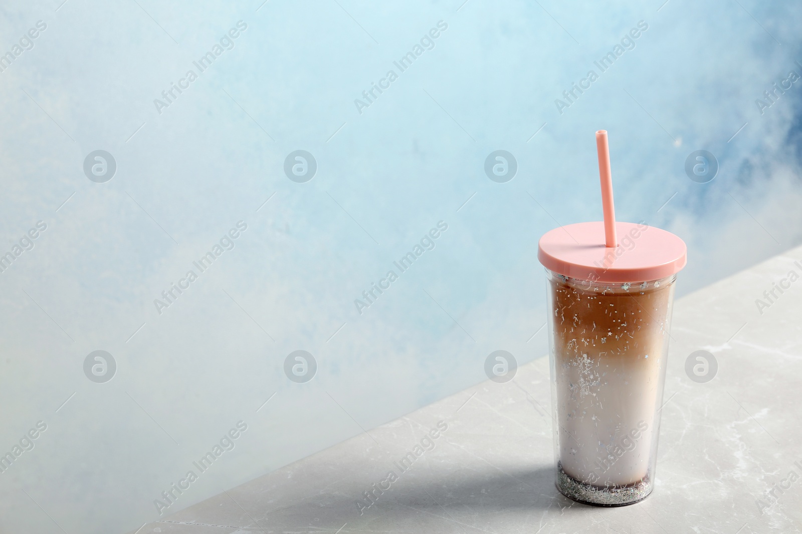 Photo of Glass of caramel macchiato on table against color background. Space for text